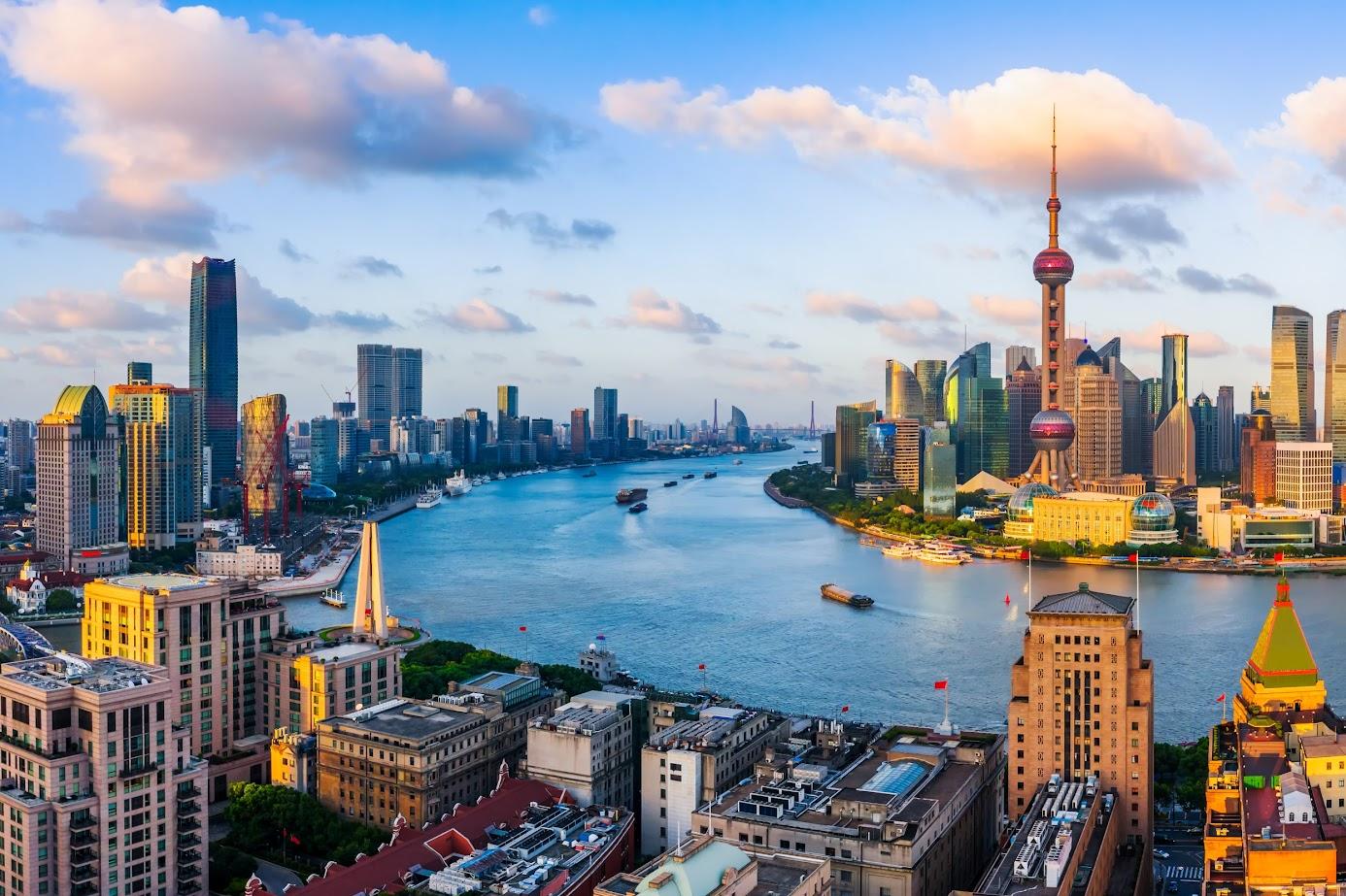 Panoramic view of Shanghai skyline with the Huangpu River and iconic Oriental Pearl TV Tower at sunset